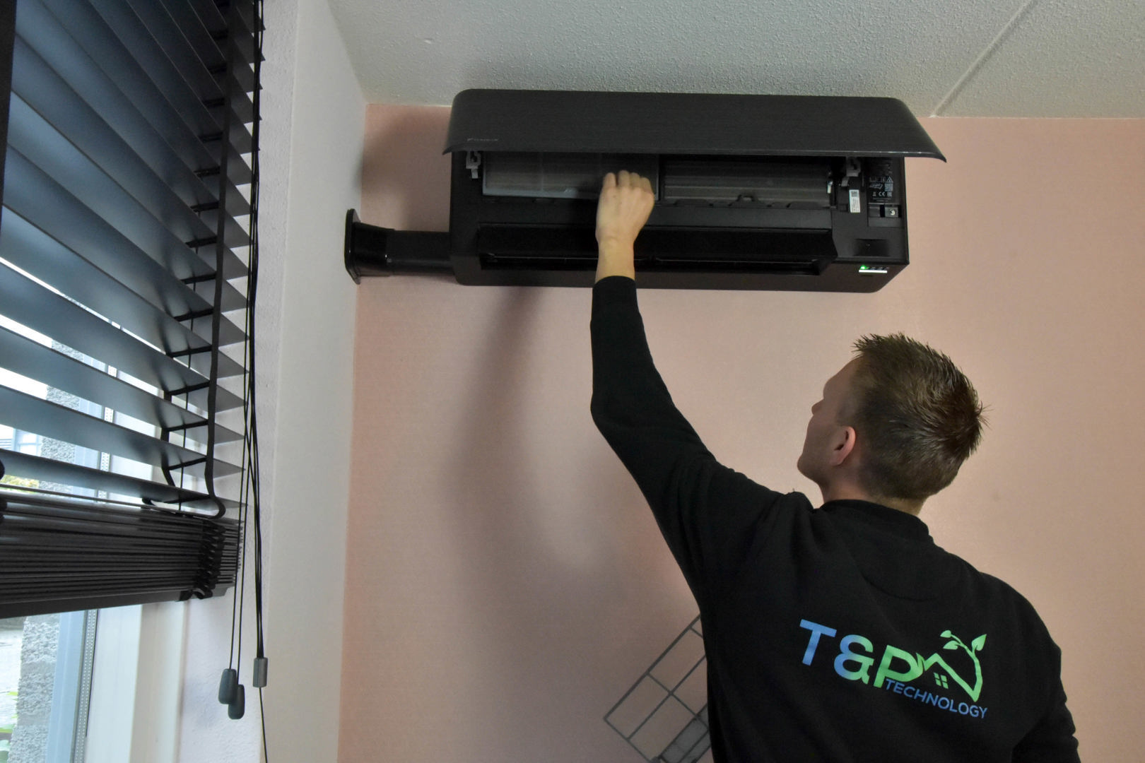 Een foto van een airco installateur die een installatie uitvoert.